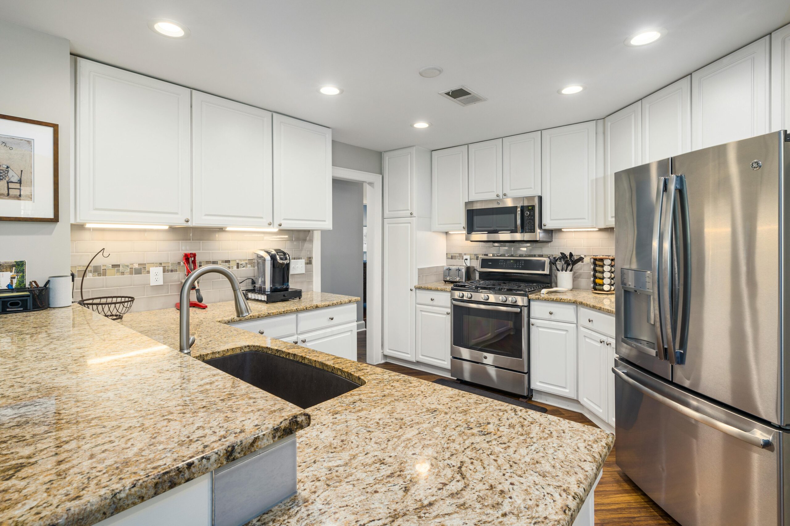 Stylish modern kitchen featuring granite countertops, stainless steel appliances, and white cabinetry.